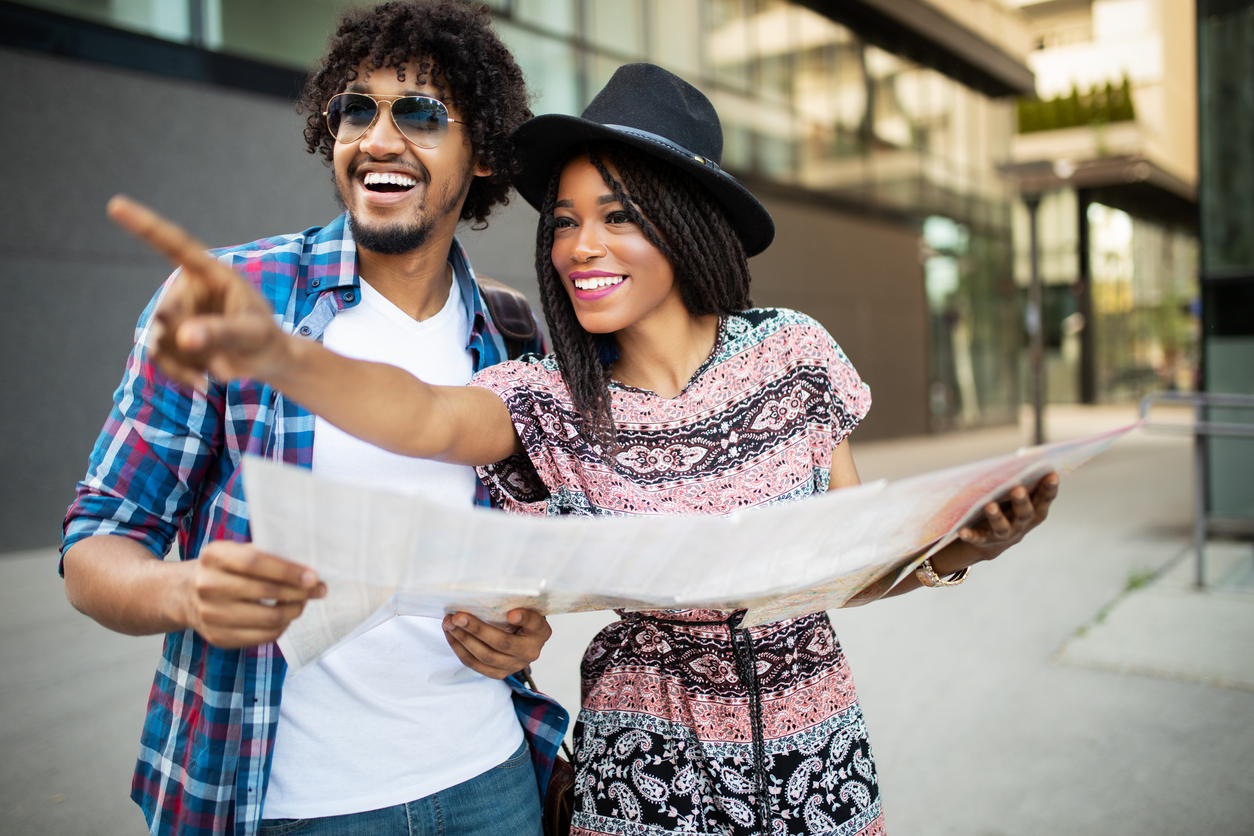 Happy black couple on vacation sightseeing city with map